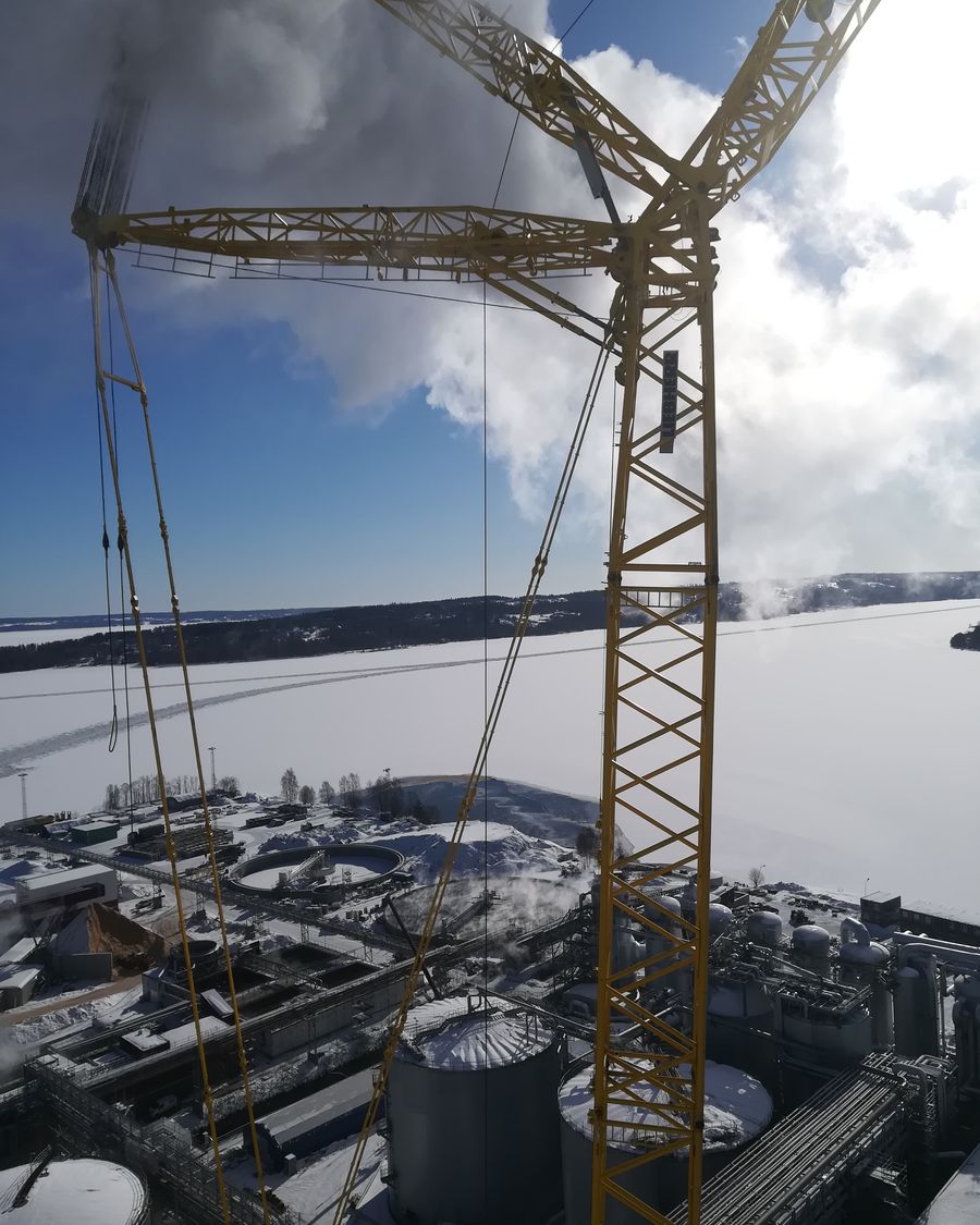 Žuta dizalica iznad industrijskog postrojenja zimi