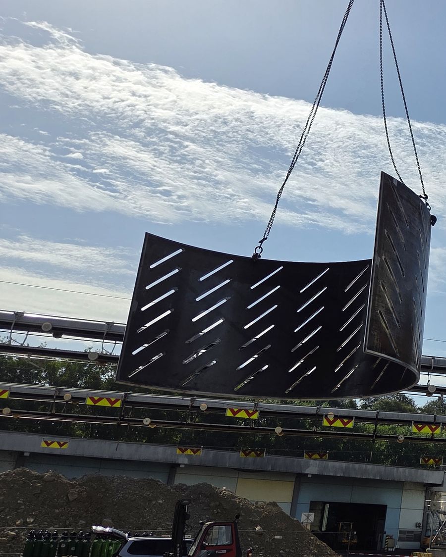 Dizalica podiže zakrivljenu čeličnu ploču na industrijskom postrojenju